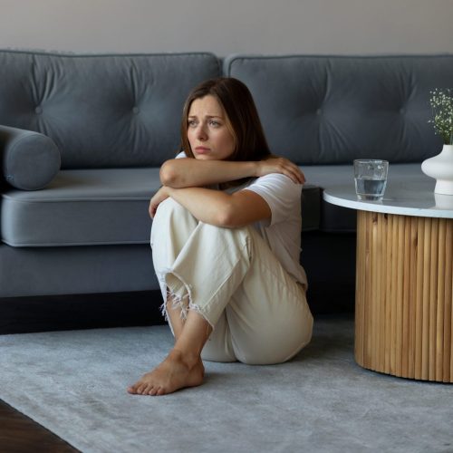 anxious-woman-sitting-floor-full-shot